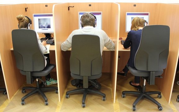 Drei Menschen sitzen jeweils vor einem Computer